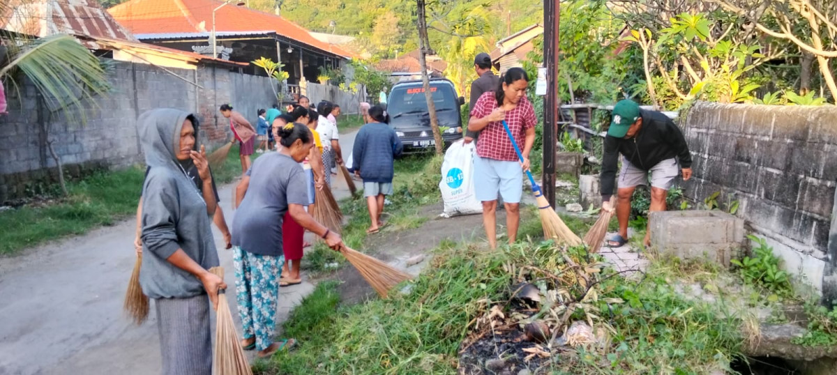 Membersihkan tumbuhan liar di pinggir jalan