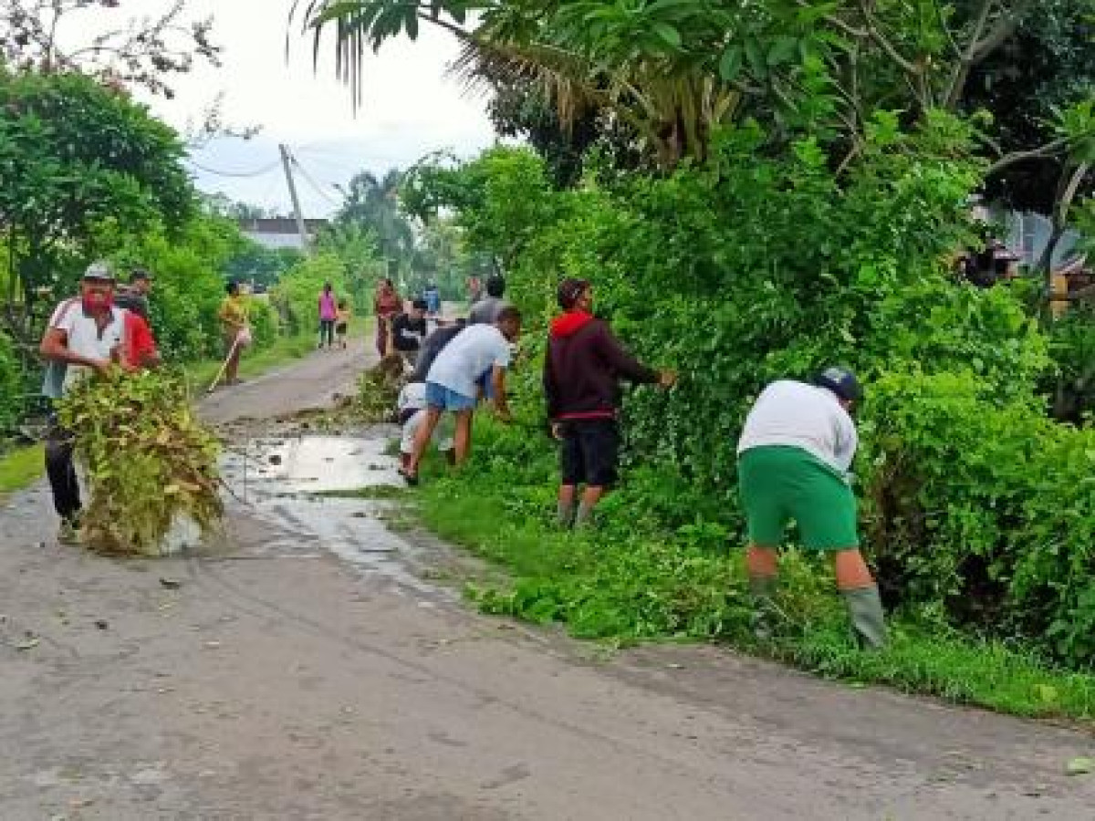 Membersihkan tumbuhan liar di sepanjang pinggir jalan