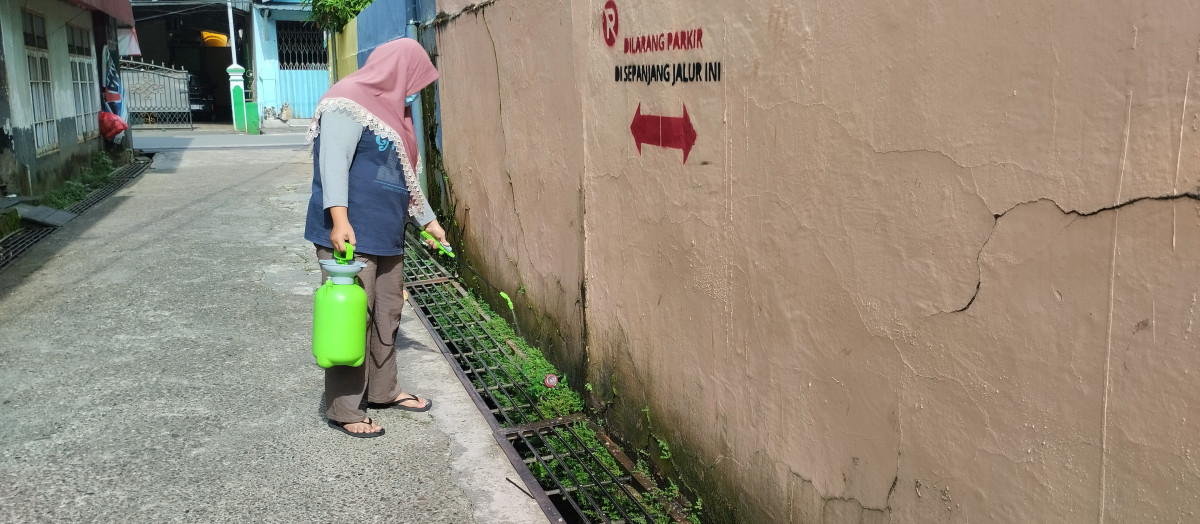 Membersihkan rumput dan sampah di lingkungan rt 06