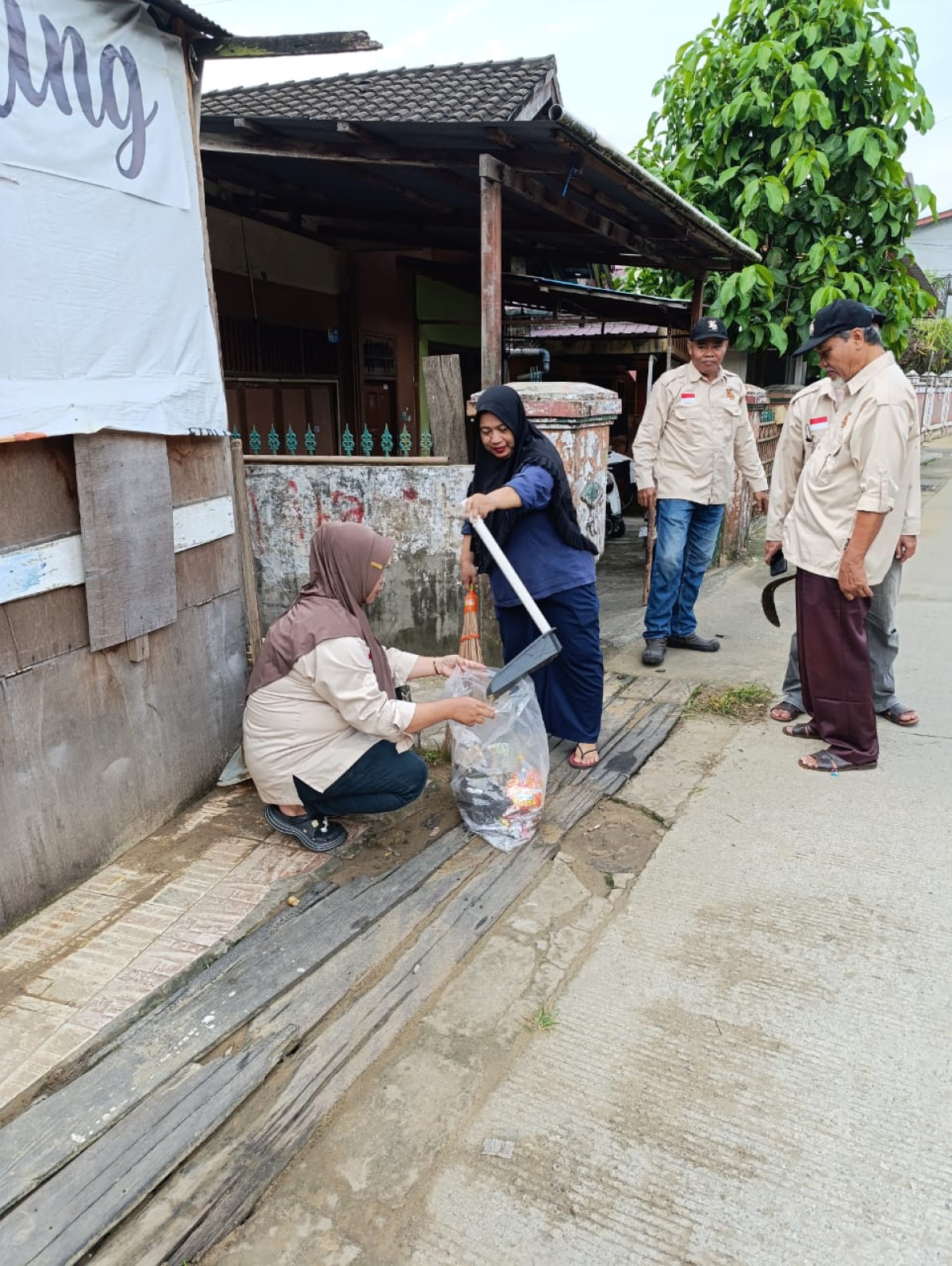 Membersihkan lapangan dan rumput dan sampah di tepi jalan raudah rt 23
