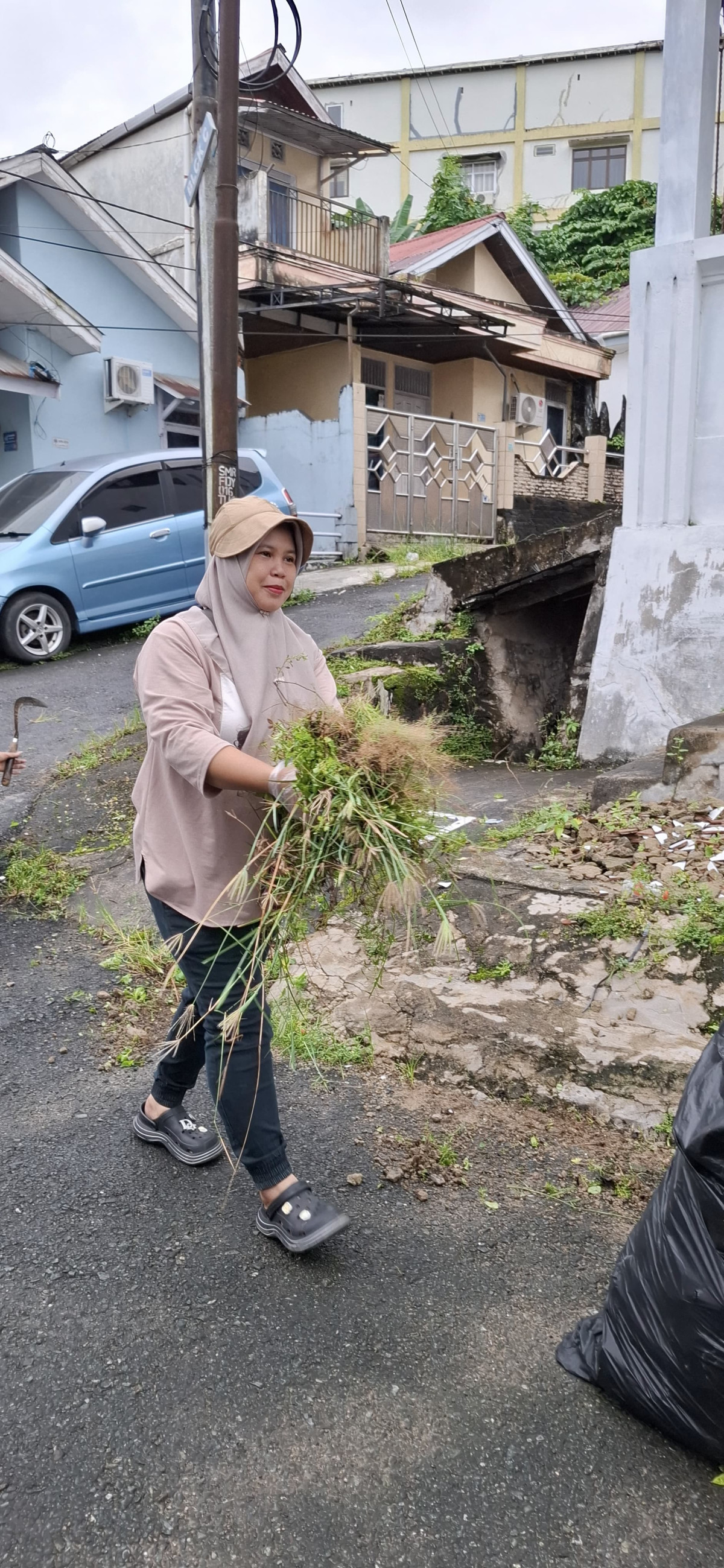 Membersihkan sampah dan rumput liar di wilayah rt 26