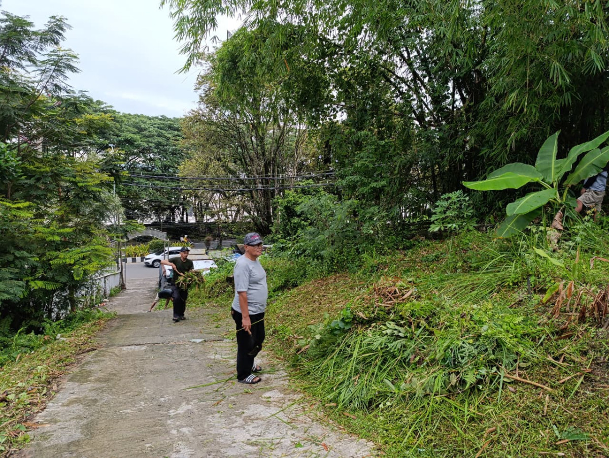 Membersihkan rumput di area RT. 01