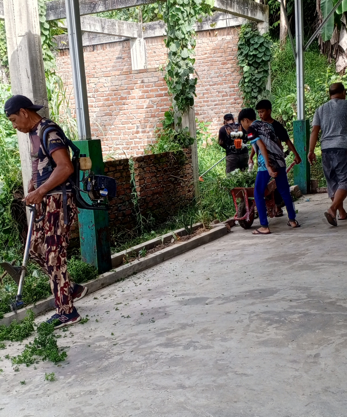 Membersihkan rumput disekitar posyandu