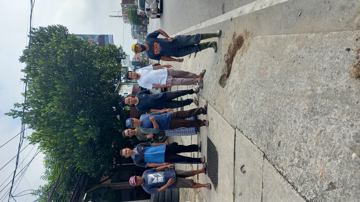 Membersihkan rumput dan sampah dipinggir jalan raya RT. 25