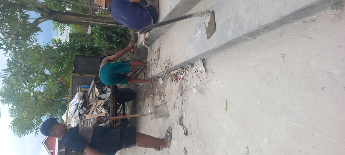 Kerja bakti membersihkan tumpukan tanah dan kayu di pinggir jalan
