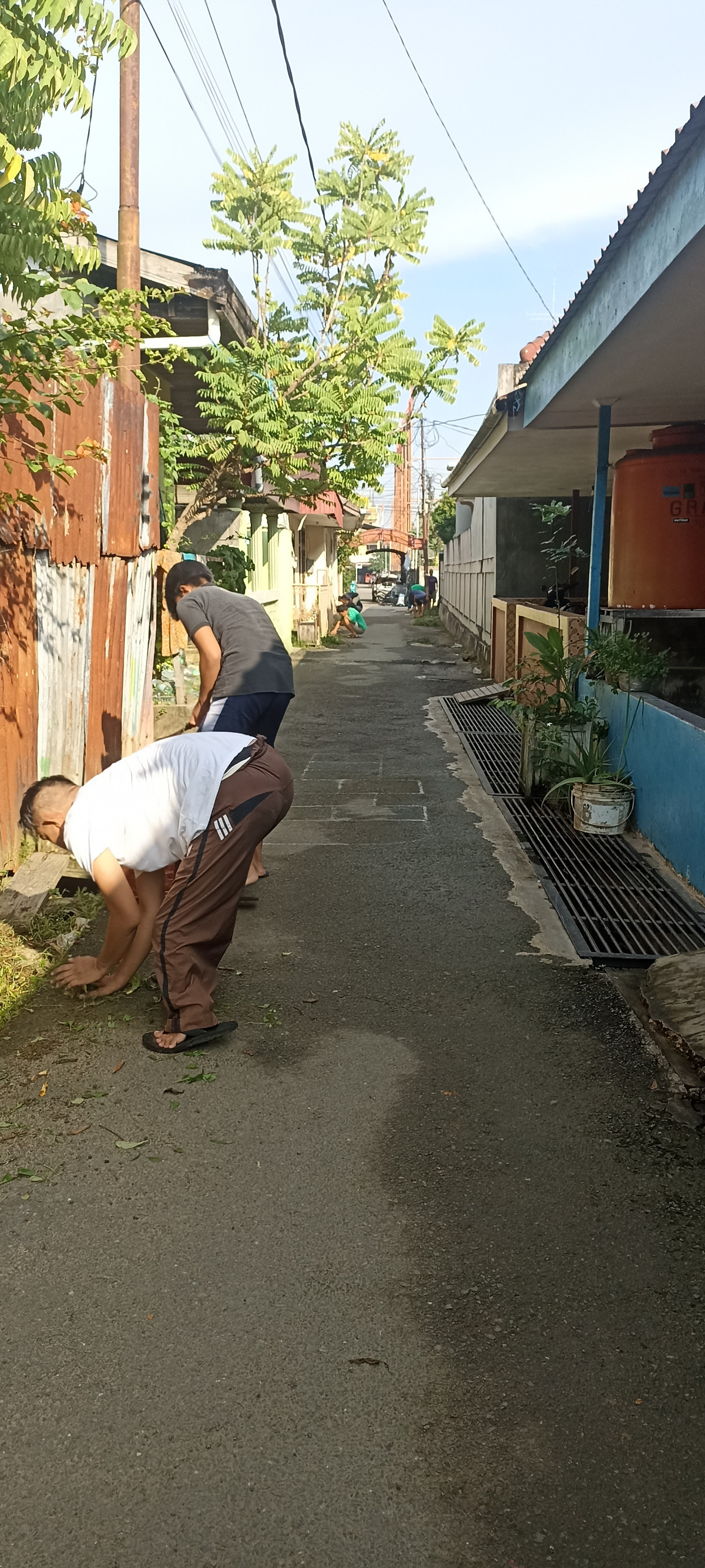 Membersihkan parit dan jalan di dalam gang