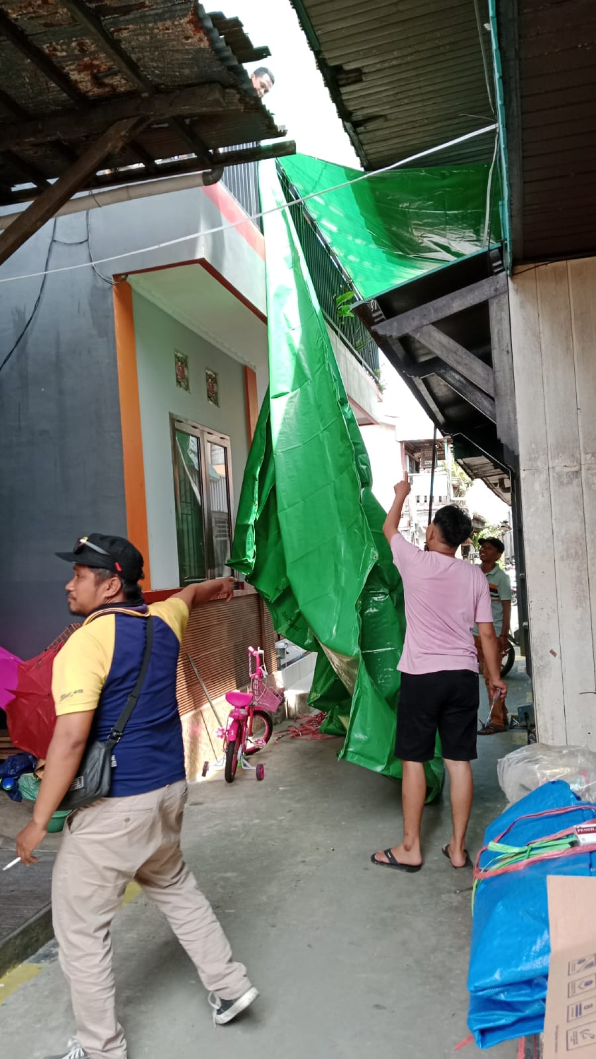 memasang terpal untuk kegiatan maulid di gang kembali