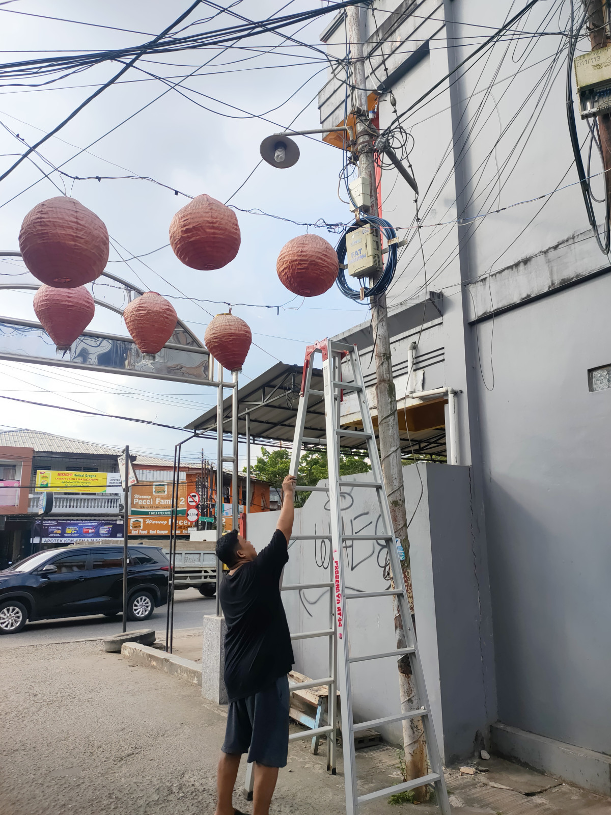 menurunkan lampu lampion yang sudah tidak dipakai/rusak