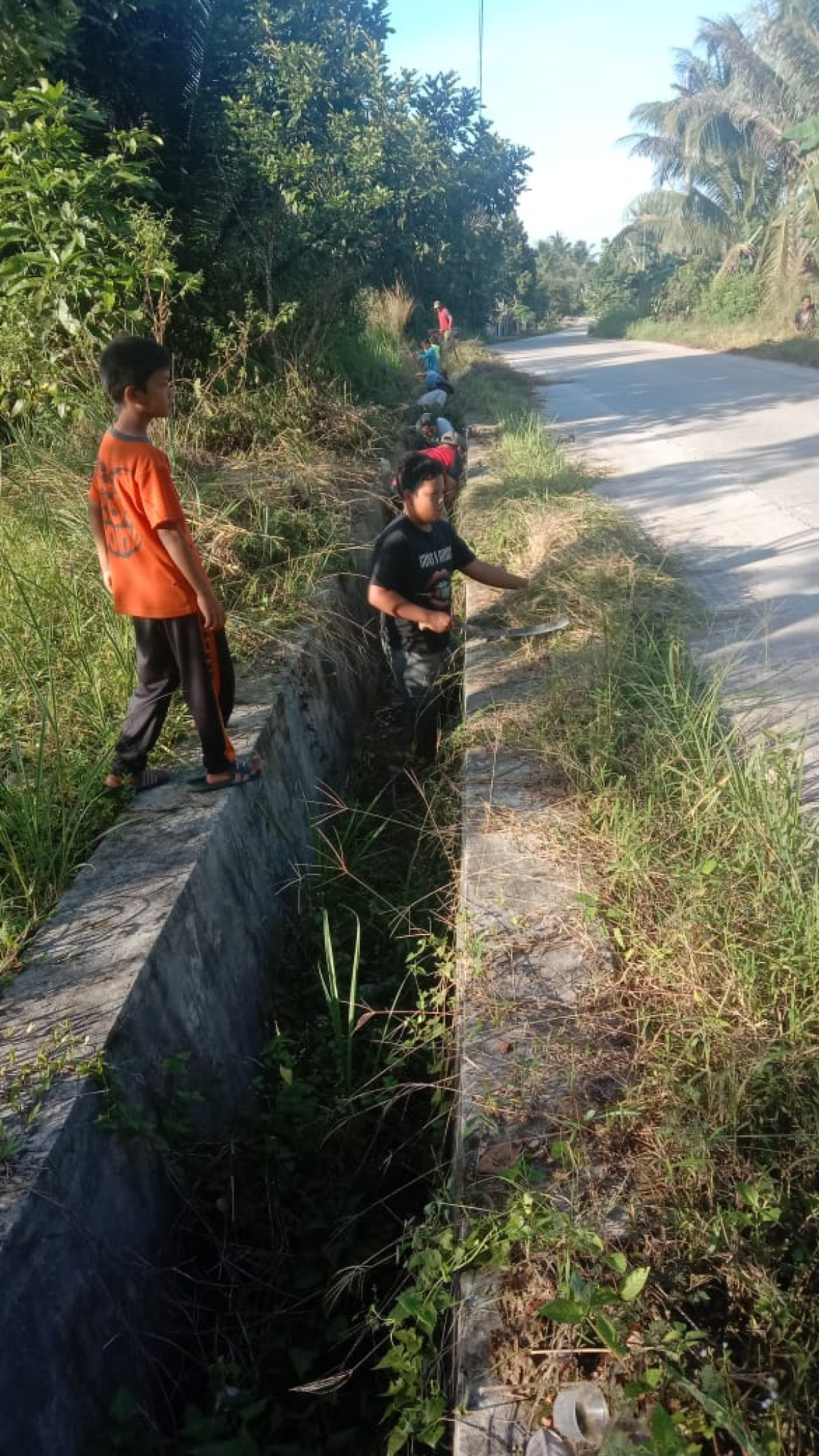 membersihkan saluran parit