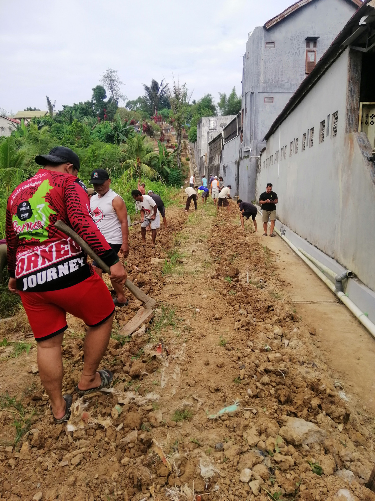 Kegiatan kerja bakti membersihkan area akses jalan masuk pemakaman di RT. 69