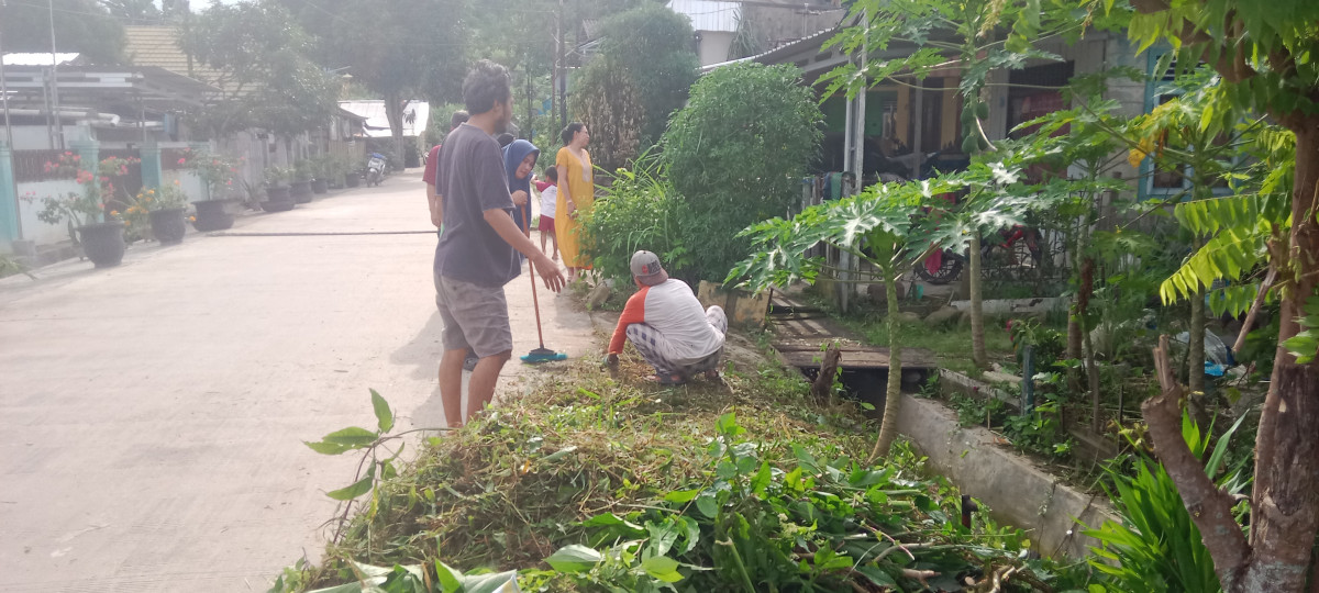 Gotong royong membersihkan rumput di pinggir jalan