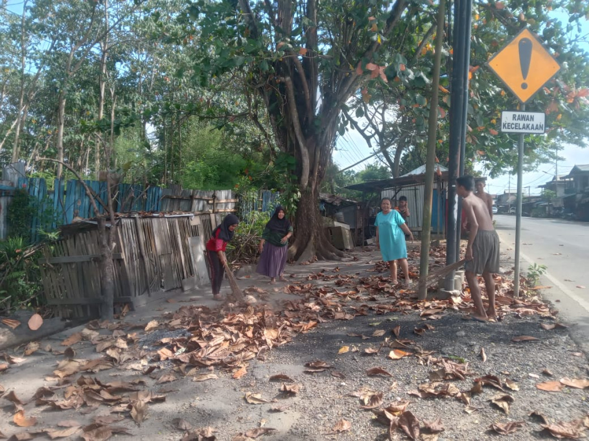 Membersihkan daun kering di pinggir jalan sekitaran rt.02